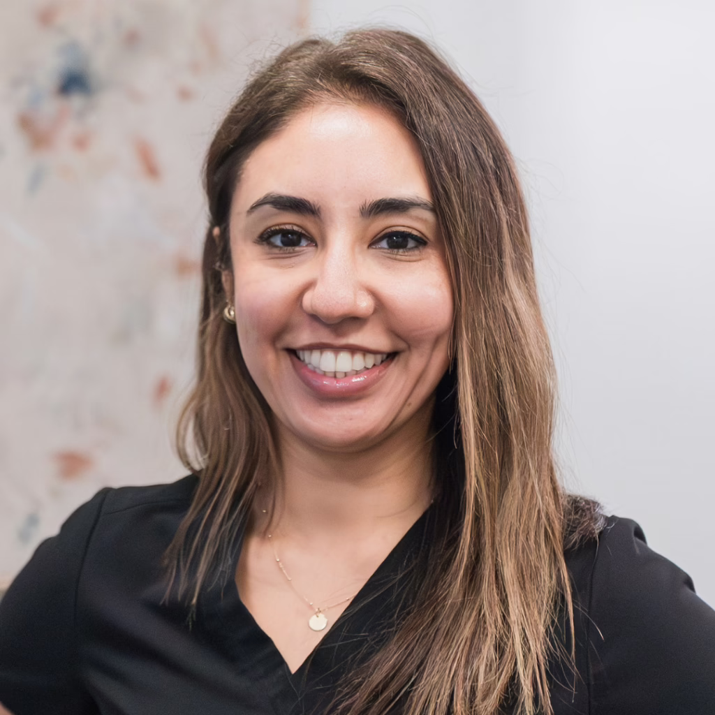 Smiling woman with long brown hair wearing a black top, posing for a portrait Photo.