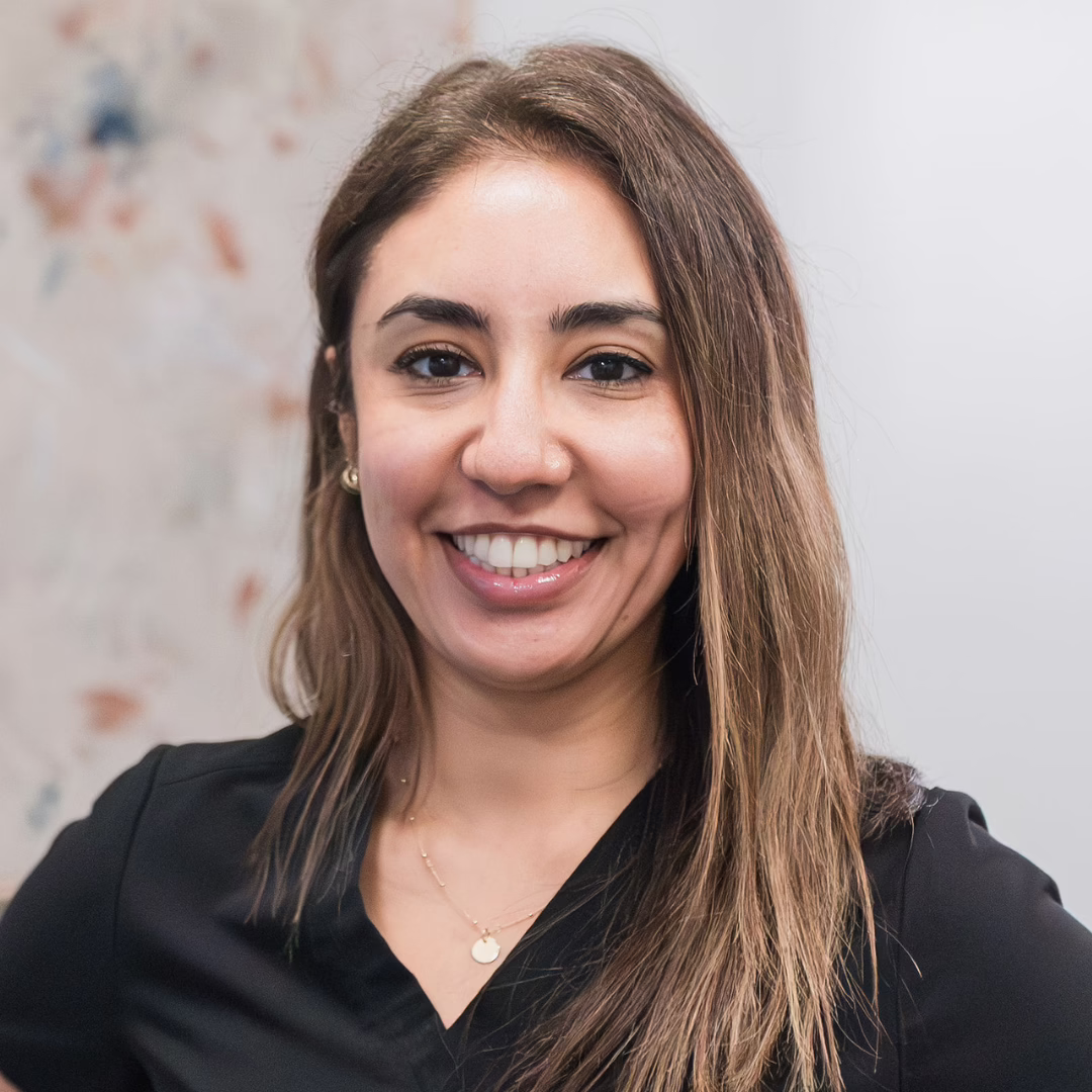 Smiling woman with long brown hair wearing a black top, posing for a portrait Photo.